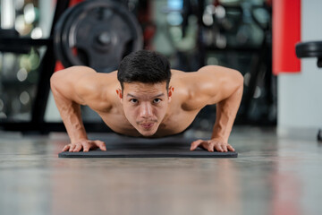Fototapeta na wymiar Sport man training doing push-ups exercise in fitness gym