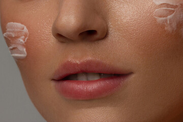 Fototapeta premium Close up of the face of a beautiful girl with perfect skin and clean all impurities thanks to moisturizing creams both anti-aging and night and day. Concept of beauty, creams,skincare and clear.