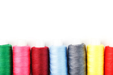 Sewing threads of different colors on reels on a white background. Free space, close-up. Isolate