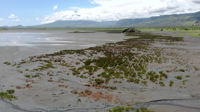Aerial Flyby View on the Maasai village in on the coast of Natron Lake front of the Ol Doinyo Lengai, Mountain of God in the Maasai language, Engare Sero village in Arusha Region i the Northern