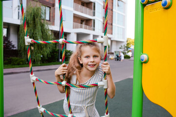 Portrait of girl climbing at the playing rope at the playground.