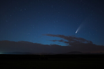 Neowise comet in the night sky at the horizon.