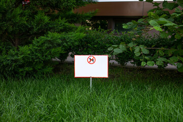 White sign about prohibition of dog's walking on green grass. Copy space.