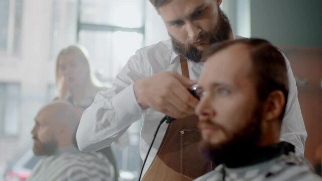 The Client Calmly Sits on the Chair and Watches the Process of a Haircut.