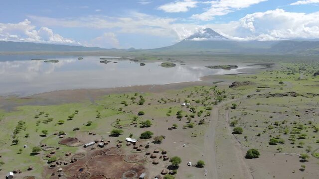 Aerial Flyby View on the Maasai village in on the coast of Natron Lake front of the Ol Doinyo Lengai, Mountain of God in the Maasai language, Engare Sero village in Arusha Region i the Northern