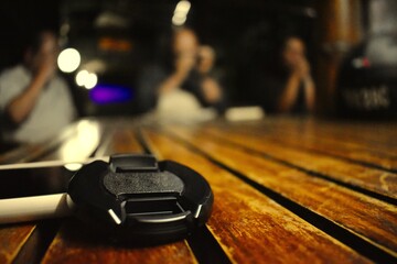 Black cover for a camera lens on a wooden table in a pub