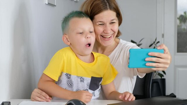 Woman and her child kid boy having fun, doing seelfie on smartphone, making funny faces
