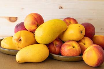 Yellow mangoes and peaches. Fresh ripe organic tropical fruits close up