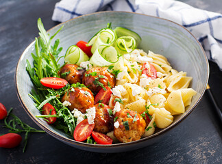 Italian pasta. Conchiglie with meatballs, feta cheese and salad on dark background. Dinner.  Slow food concept