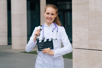 The girl doctor holds a movie flap in her hands. The concept of shooting a film about medicine