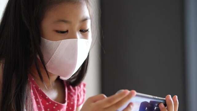 asian girl wear mask watching mobile at home, education and new normal concept.