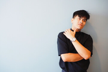 Young smart Asian male model with his arms crossed looking at and thinking something on light blue wall background with copy space