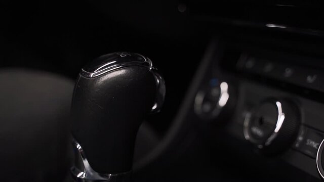 Static close up 4k shot of a hand in a black rubber glove wiping and polishing a shiny black gearshift stick of a new luxurious car using a blue rag. Car gearshift cleaning with a blue rag.