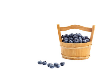 Blueberries in a wooden basket. Some blueberries spilled out. On a white background, isolated on white.
