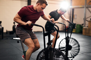Fototapeta na wymiar Young men exercising on stationary bikes at the gym