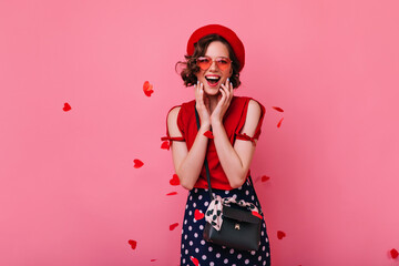 Excited french girl with black handbag expressing happiness in valentine's day. Studio photo of joyful white lady wears trendy beret.