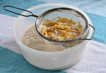 Sieve full of pasta with flour going through