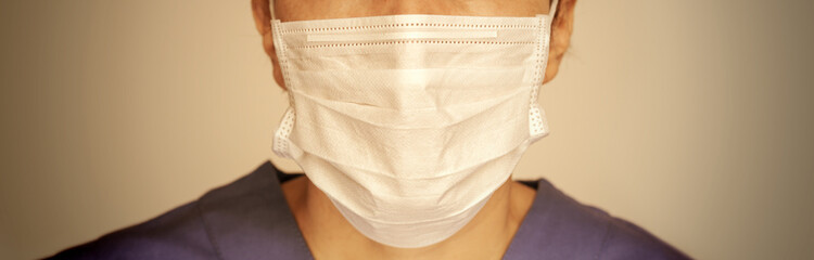 tight close up of a female physician or nurse wearing a protective face mask, concept of prevention and protection of epidemic spread