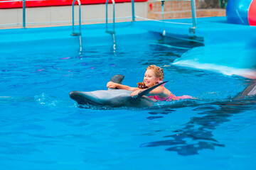 Happy little girl swimming with dolphins in Dolphinarium