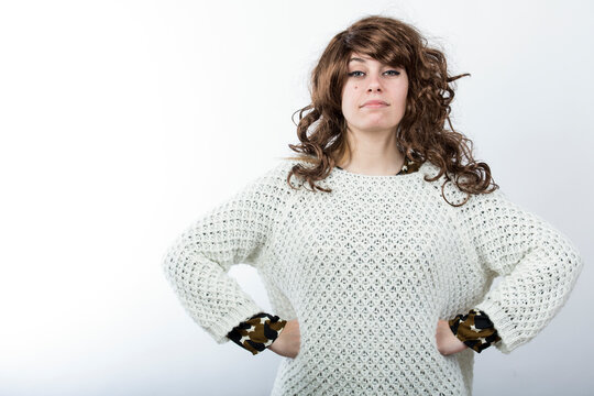 Signora con capelli mossi castani e maglione sguarda con espressione molto severa , isolata su sfondo bianco 