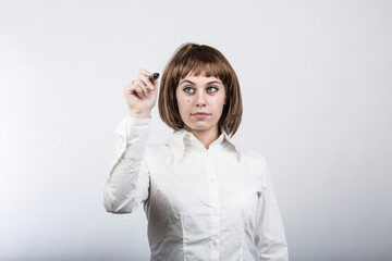 Ragazza chiara con capelli a caschetto e camicia bianca scrive qualcosa con un pennarello in un ipotetica parete trasparente, isolata su sfondo bianco