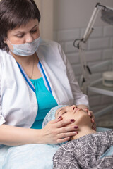 A young girl is cleaning the skin of her face at a cosmetologist. Facial cleansing and massage