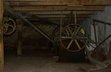 Obraz premium old, rusty mechanisms of an abandoned water mill. wheels and belts of mechanisms are visible