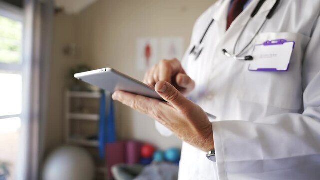 Caucasian doctor in surgeon coat on digital tablet capturing medical data
