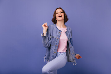 Beautiful excited lady dancing on violet background. Indoor portrait of gorgeous brunette woman in oversize jacket.