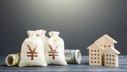 Yen Yuan money bags and residential buildings figures. Investments in real estate. Financing the...
