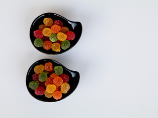 Sweet mixed color jelly candy in a black bowl against white background with copy space