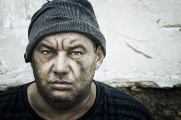 Portrait of a homeless man in a knitted hat. Look at the camera.