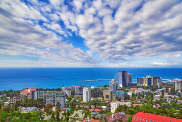 Blue coast of Black Sea in Sochi city with residential houses and recreation areas under summer cloudy sky