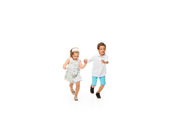 Fototapeta premium Happy children, little and emotional caucasian boy and girl jumping and running isolated on white background. Look happy, cheerful, sincere. Copyspace for ad. Childhood, education, happiness concept.