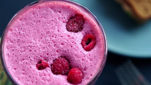 Refreshing raspberry smoothie beverage filmed from above on table.Delicious cocktail with fresh raspberries for lunch.Healthy detox drink with natural organic ingredients.Cold milkshake for summer