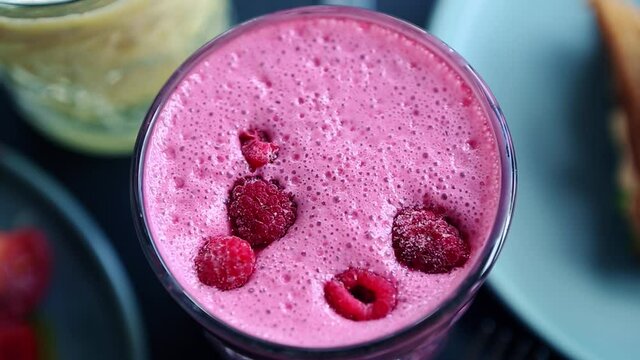 Video clip of detox smoothie drink with  raspberries.Footage of delicious raspberry milkshake for breakfast.Purple beverage with fresh berries for detoxication diet meal