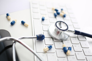 Focused photo on metal part of stethoscope that being on keyboard, working place of practitioner