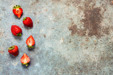 strawberries and halves on a blue metal background. Healthy lifestyle and summer diet detox food concept