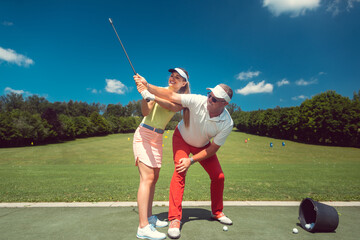 Golf pro teaching a woman student of the driving range