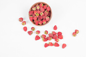 Raspberries in a pottery bowl and on the white background