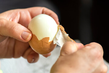 Hands peeling hard boiled eggs