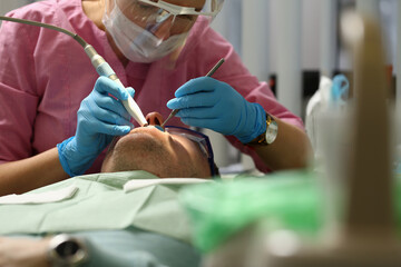 Close up of professional stomatologist that using sterile instrument while treating bad teeth of...