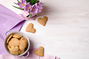 lilac crocuses and sesame dry cookies in the form of heart on a light wooden table