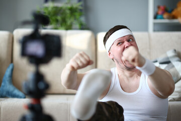 Serious male person wearing wristband while controlling his pulse and making faces on camera