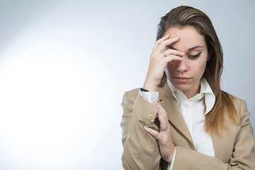 Manager donna bionda in giacca beige si porta la mano alla fronte e guarda in basso con espressione...