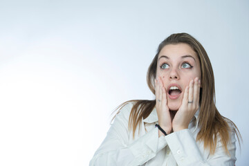 ragazza bionda con camicia bianca si porta le mani alla faccia e guarda lontano con aria...