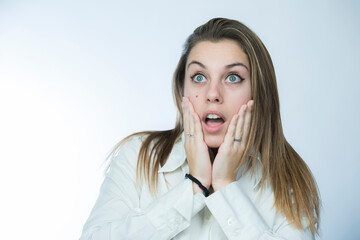 ragazza bionda con camicia bianca si porta le mani alla faccia e guarda lontano con aria...