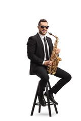 Naklejka premium Man sitting on a chair with a saxophone and smiling at the camera