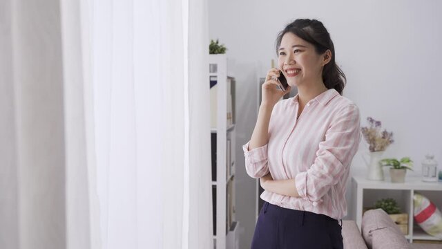 japanese businesswoman having business talk on cell phone with gestures. asian professional lady looking outside window while communicating with the major patron