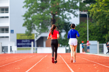 Obraz premium Two girls running in the morning at the stadium